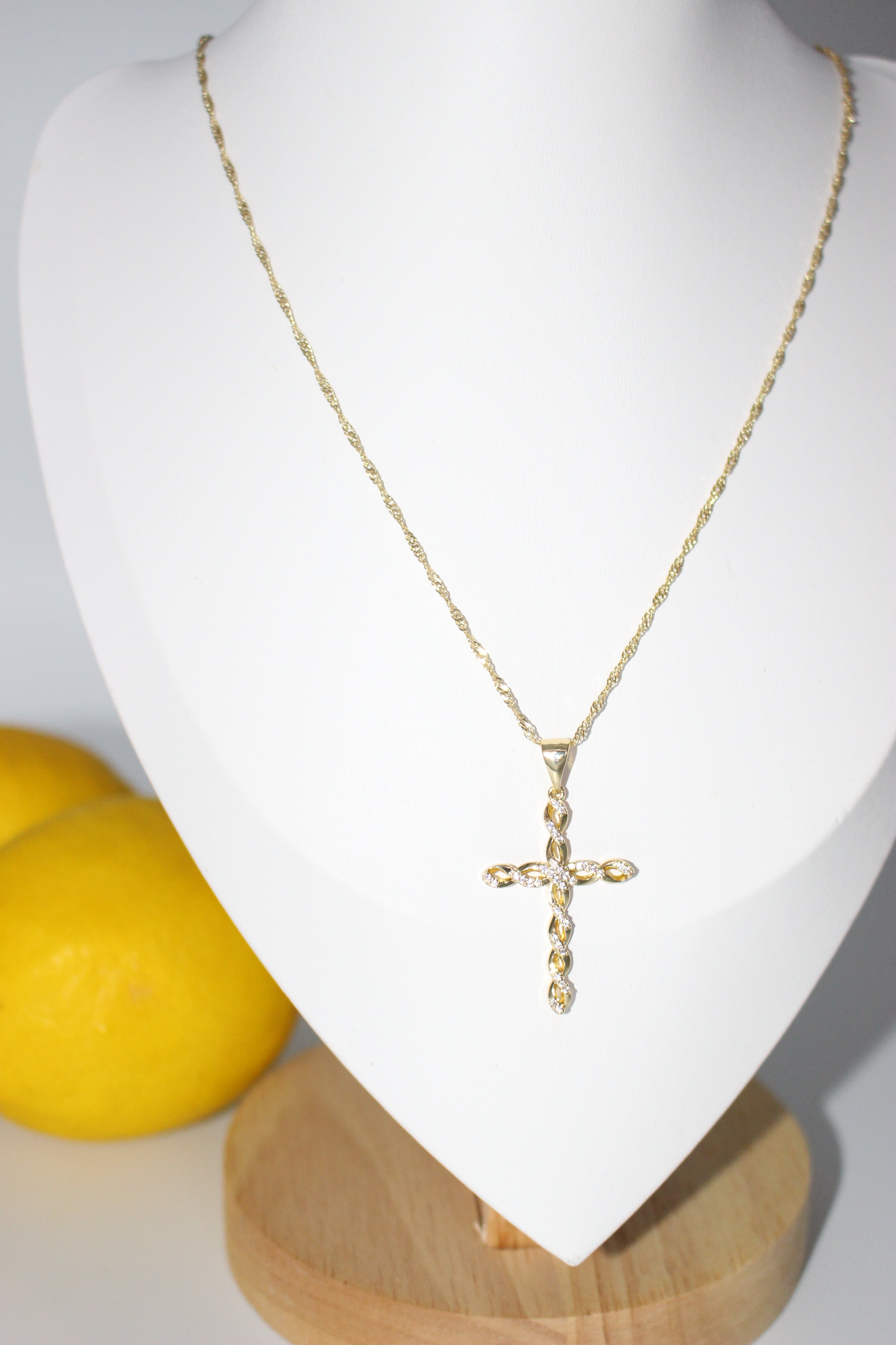 Gold necklace on a mannequin bust with a lemon in the background