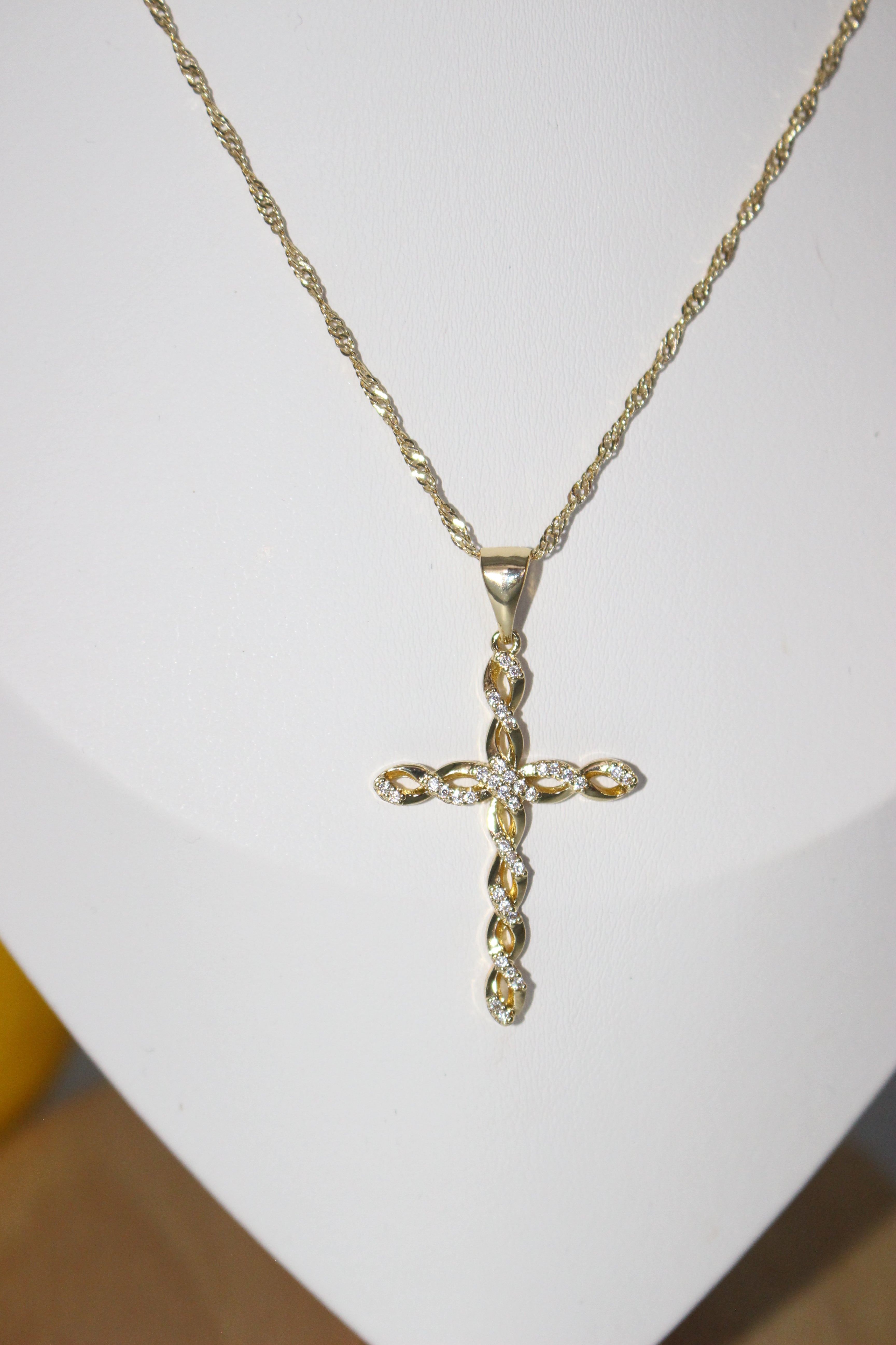 Gold cross necklace on a white surface