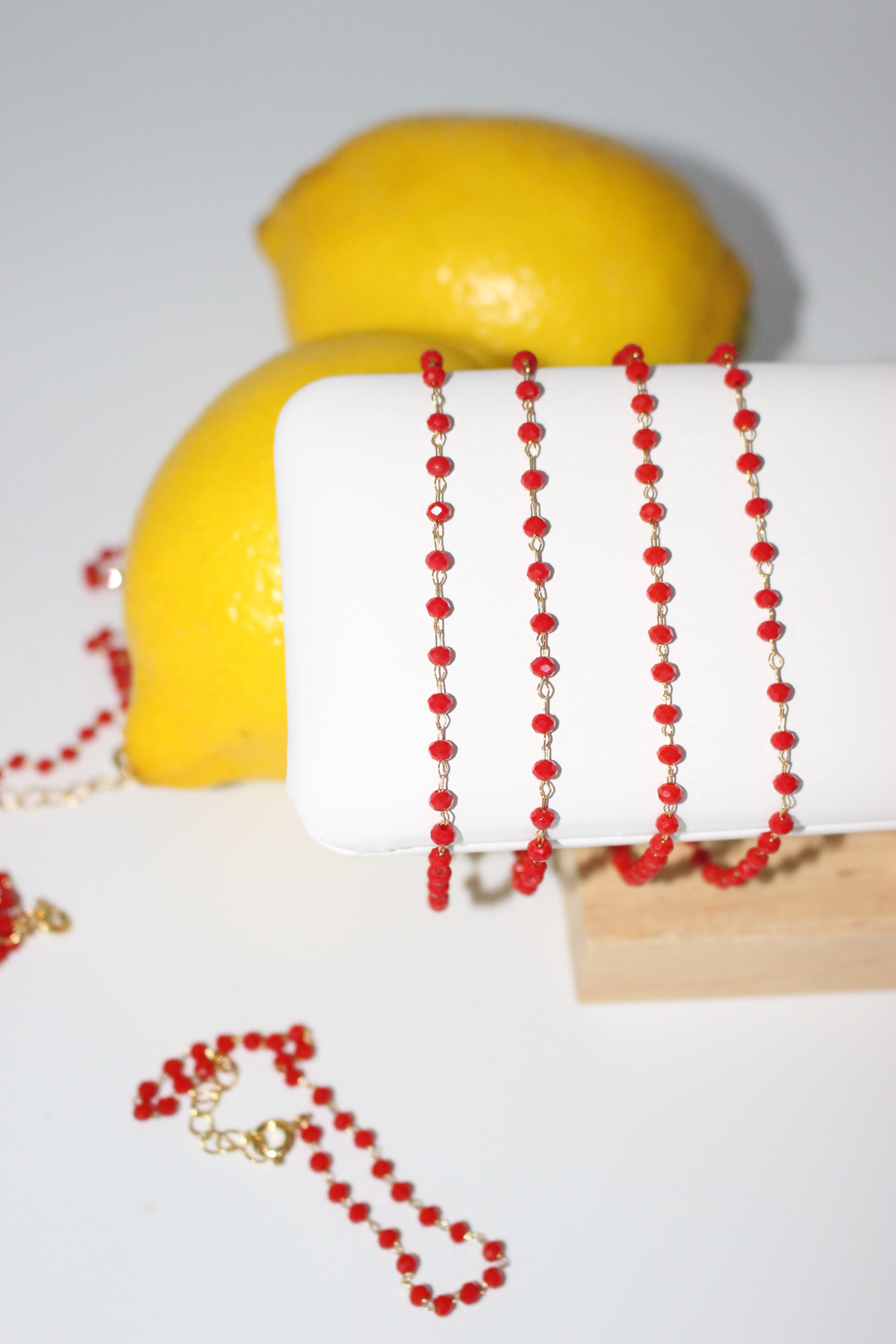 Red crystal bracelet on white surface with lemons in the background.