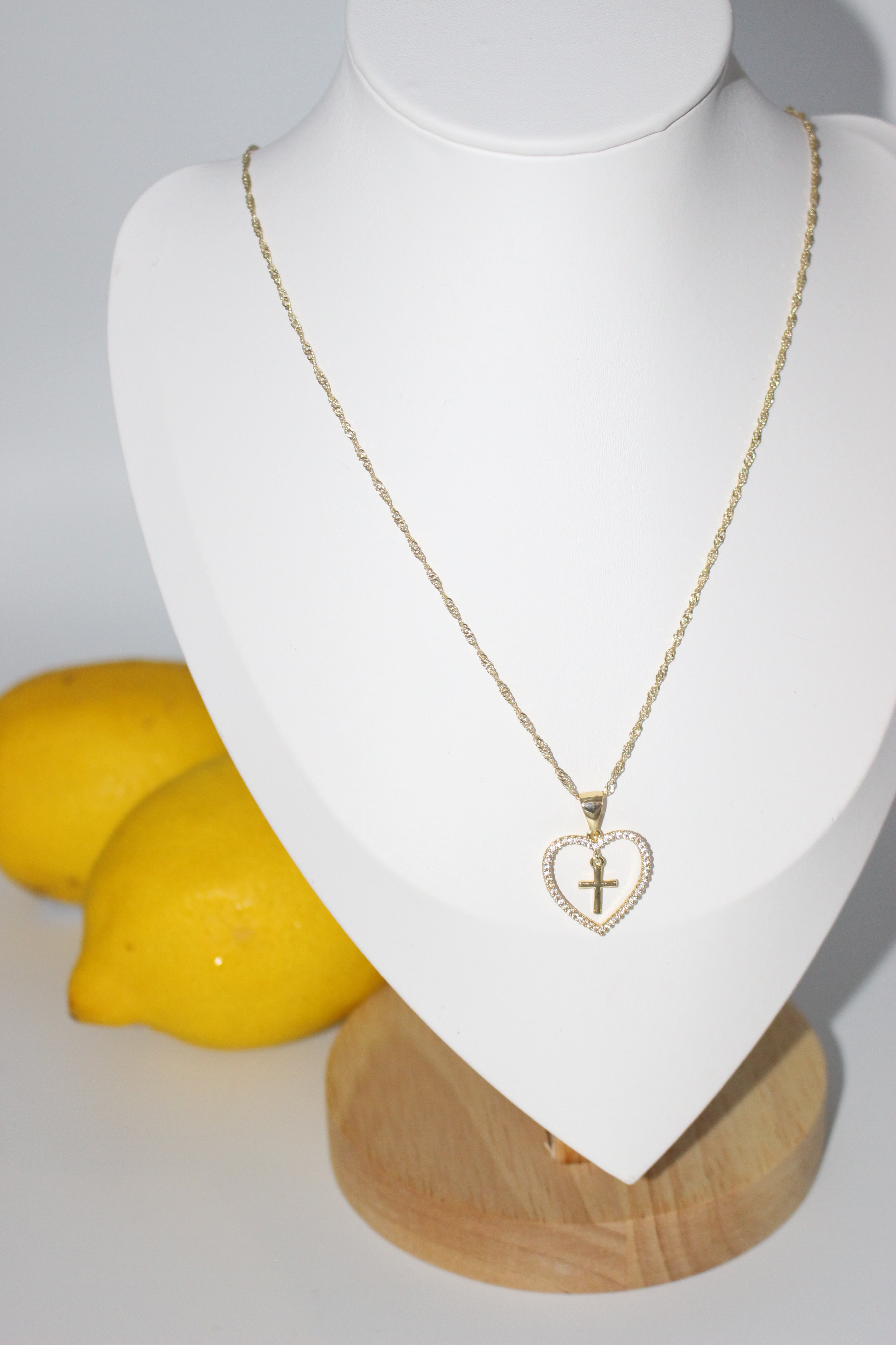 Gold necklace on white stand with lemons in the background