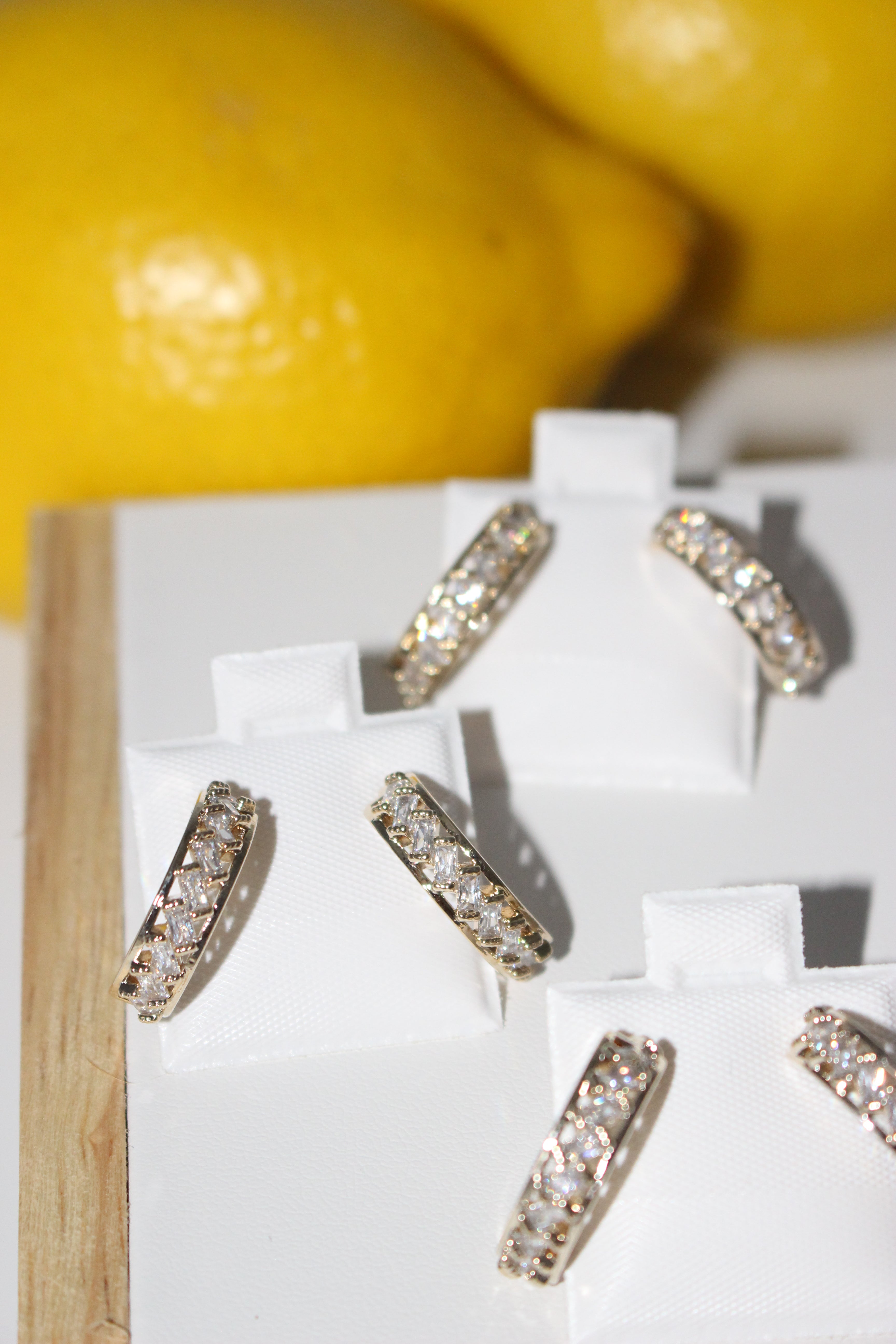 Gold and diamond earrings on a white cloth with a lemon in the background