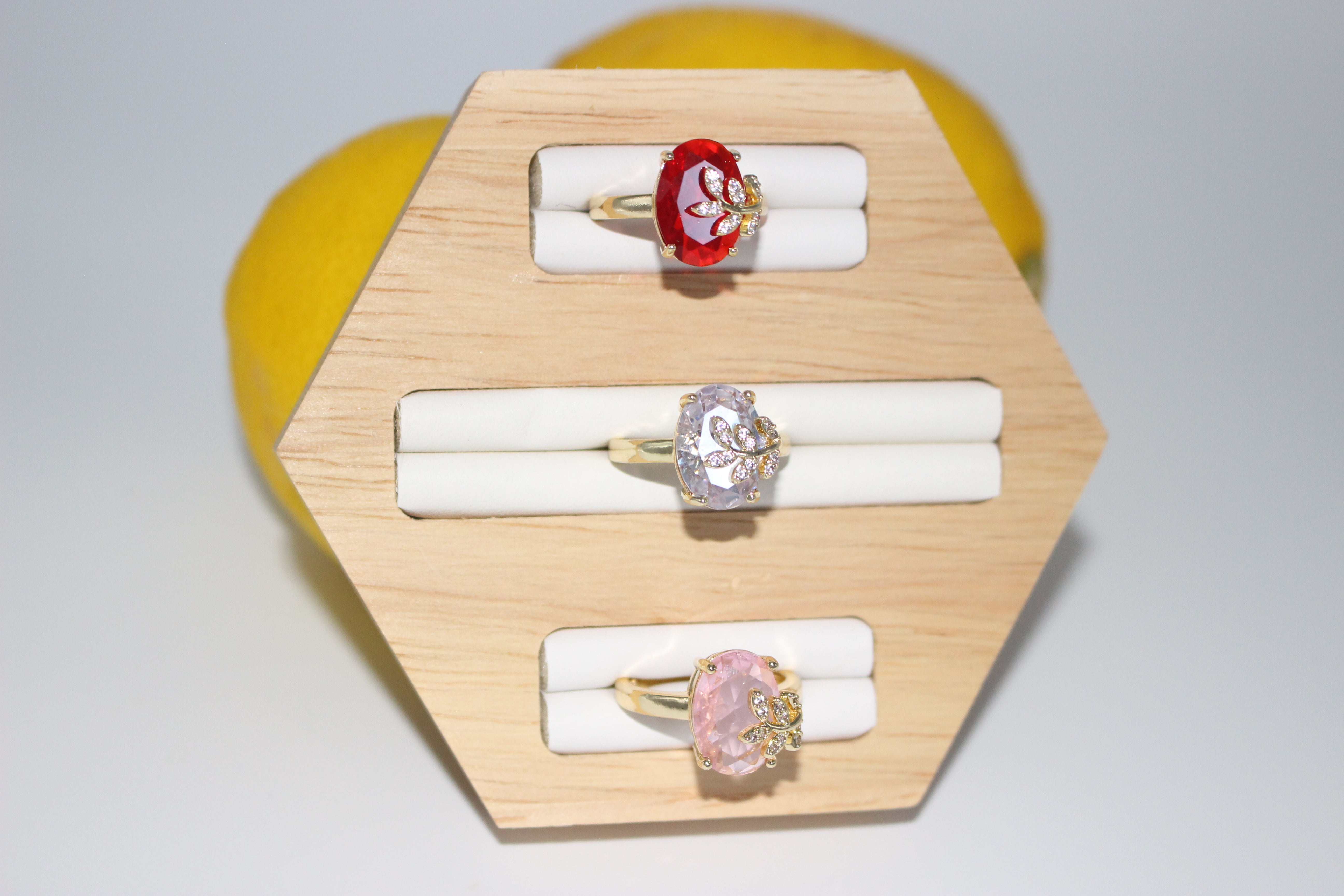 Three rings on a wooden ring holder with a yellow heart-shaped object in the background.
