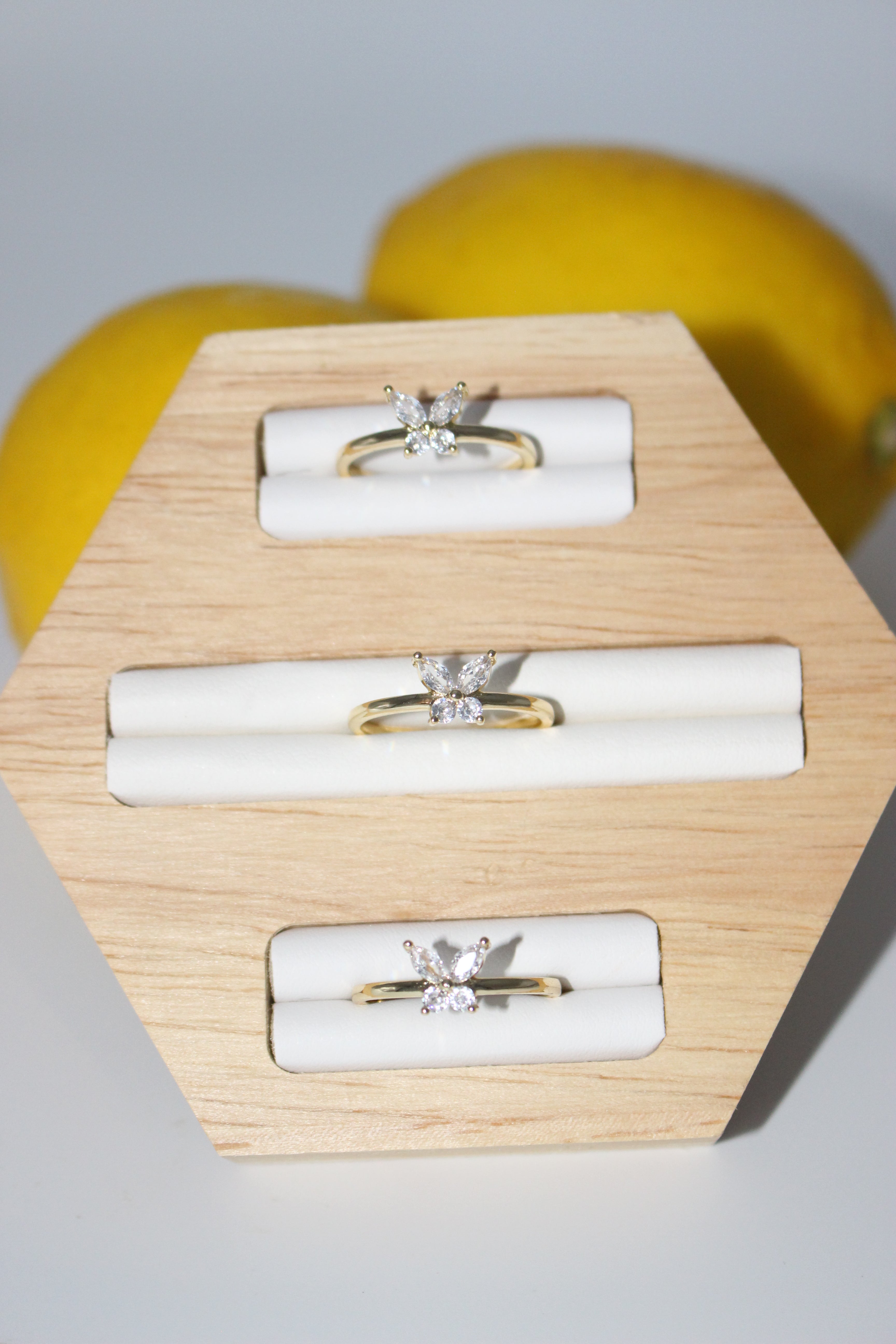 Three gold rings displayed on a wooden stand with a white background