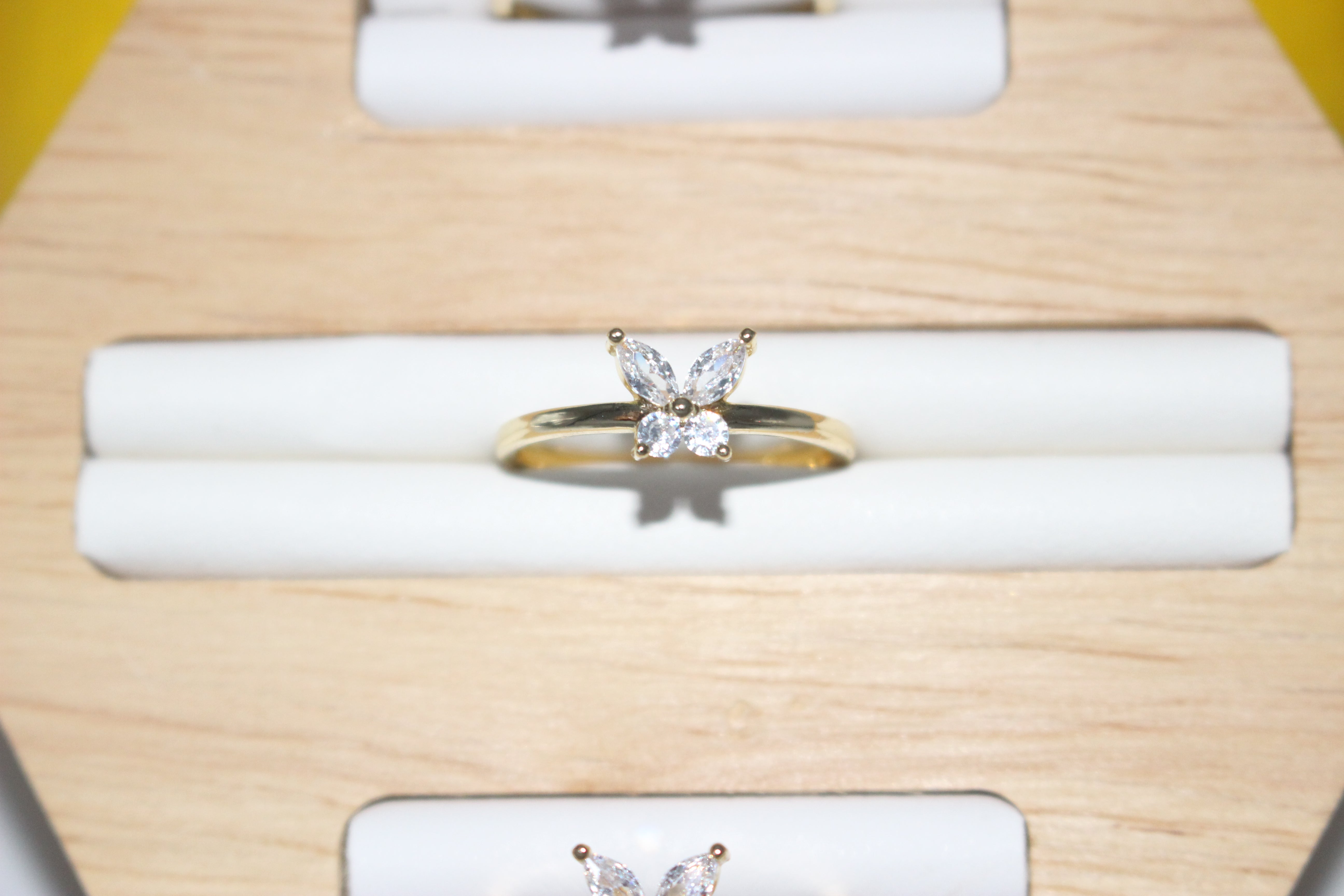 Gold ring with butterfly design on a white cushion inside a wooden box