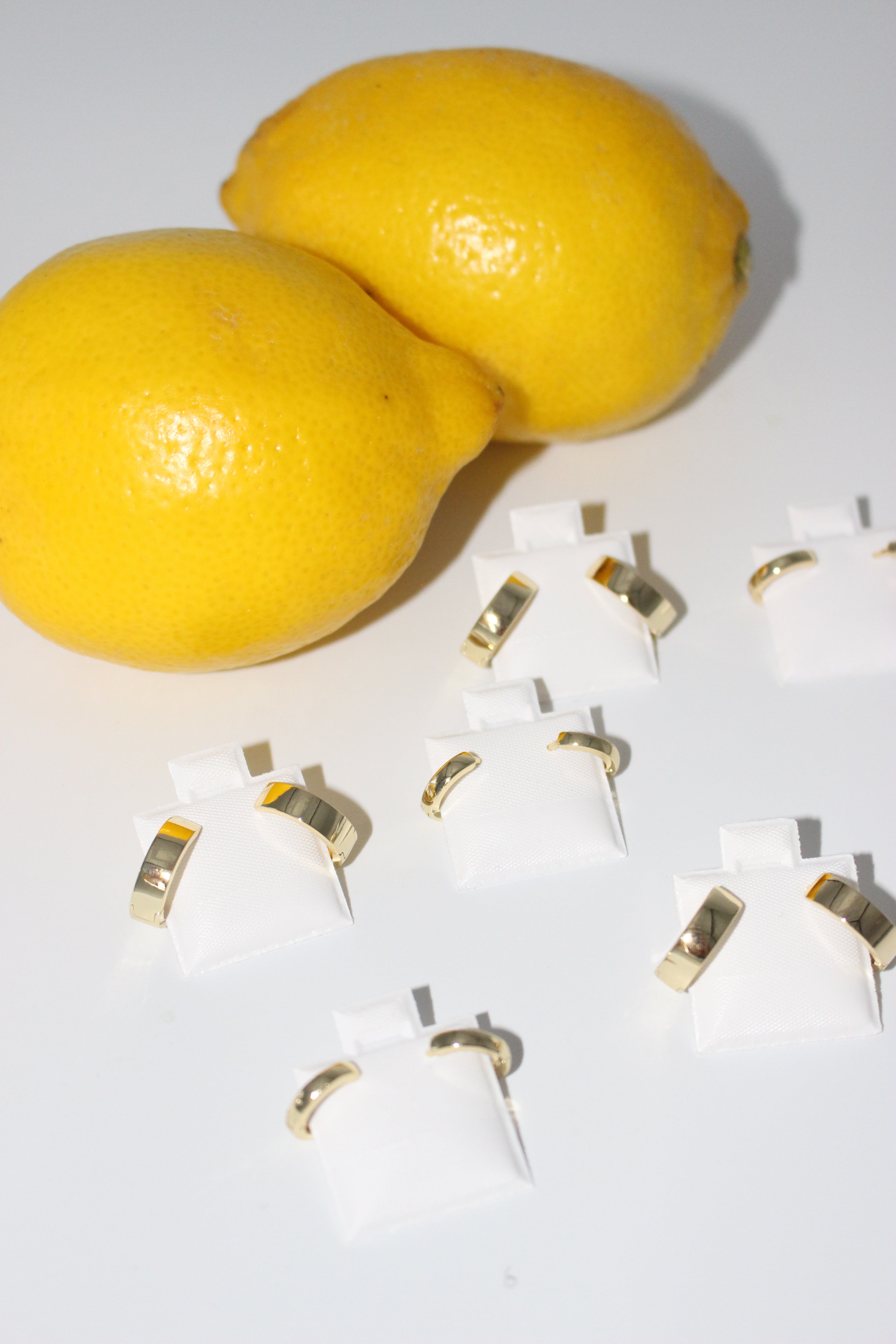 Two lemons on a white background with gold earrings.