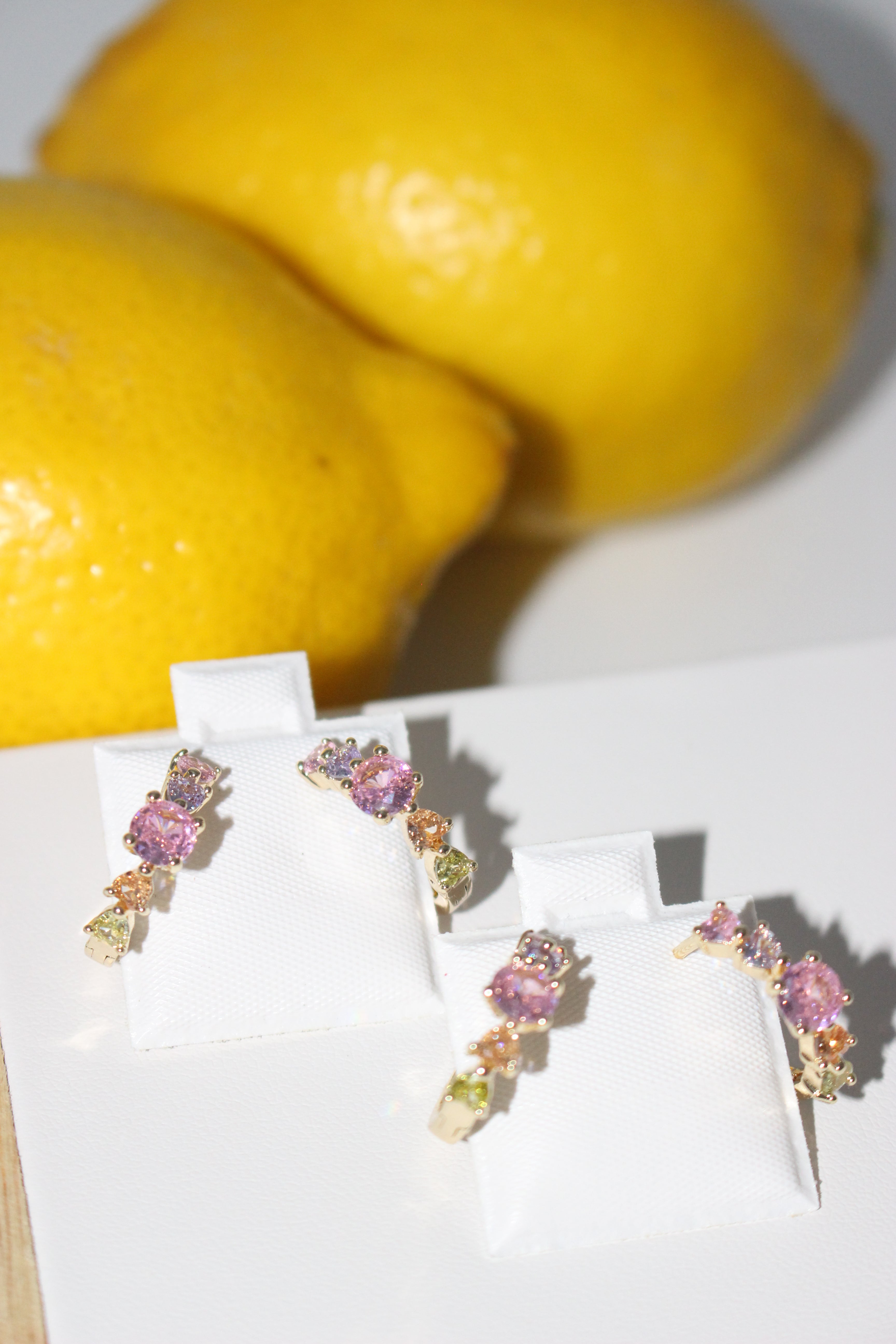 Colorful earrings displayed on a white card with lemons in the background