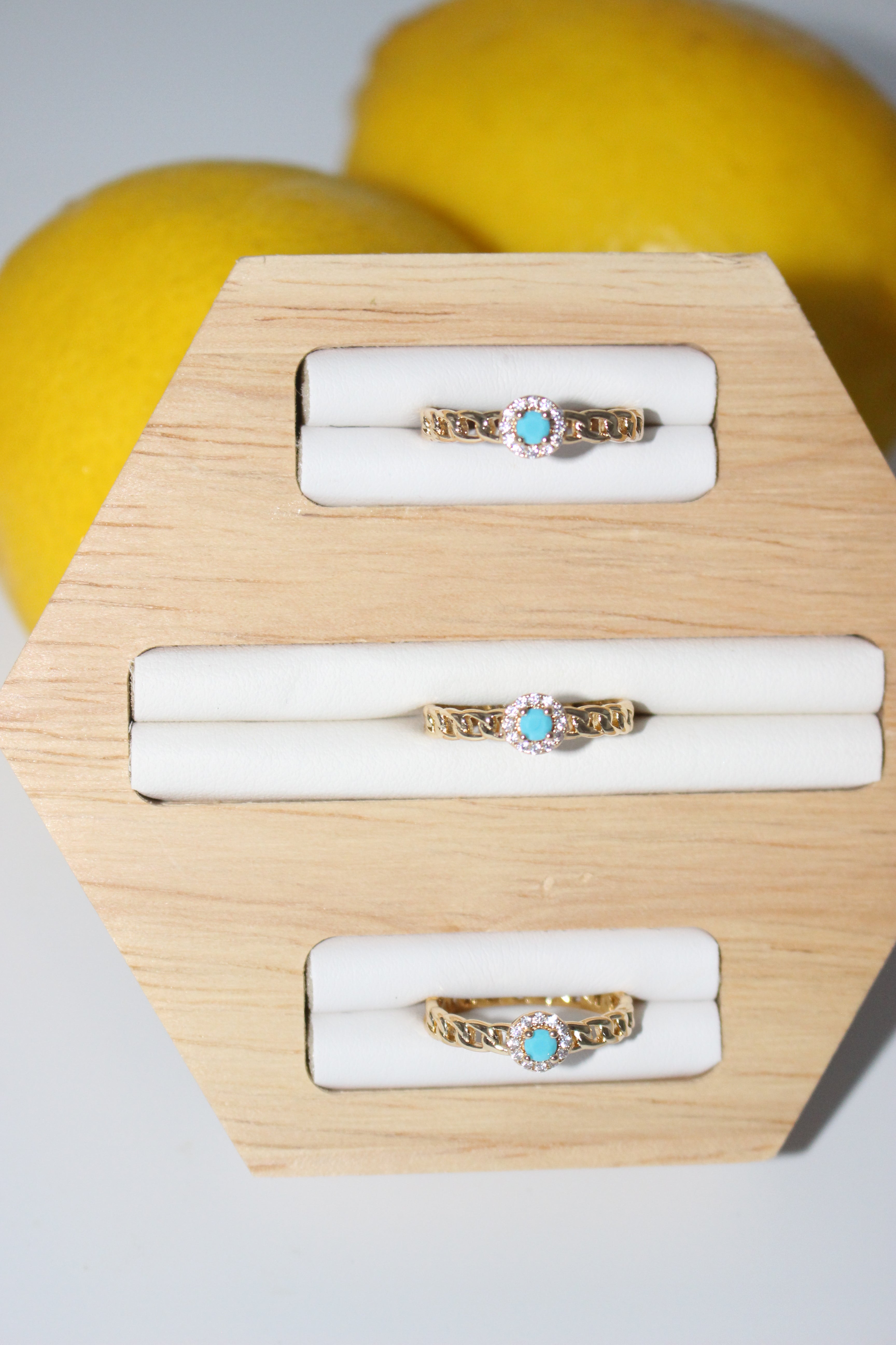 Gold rings with turquoise stones on a wooden display block.