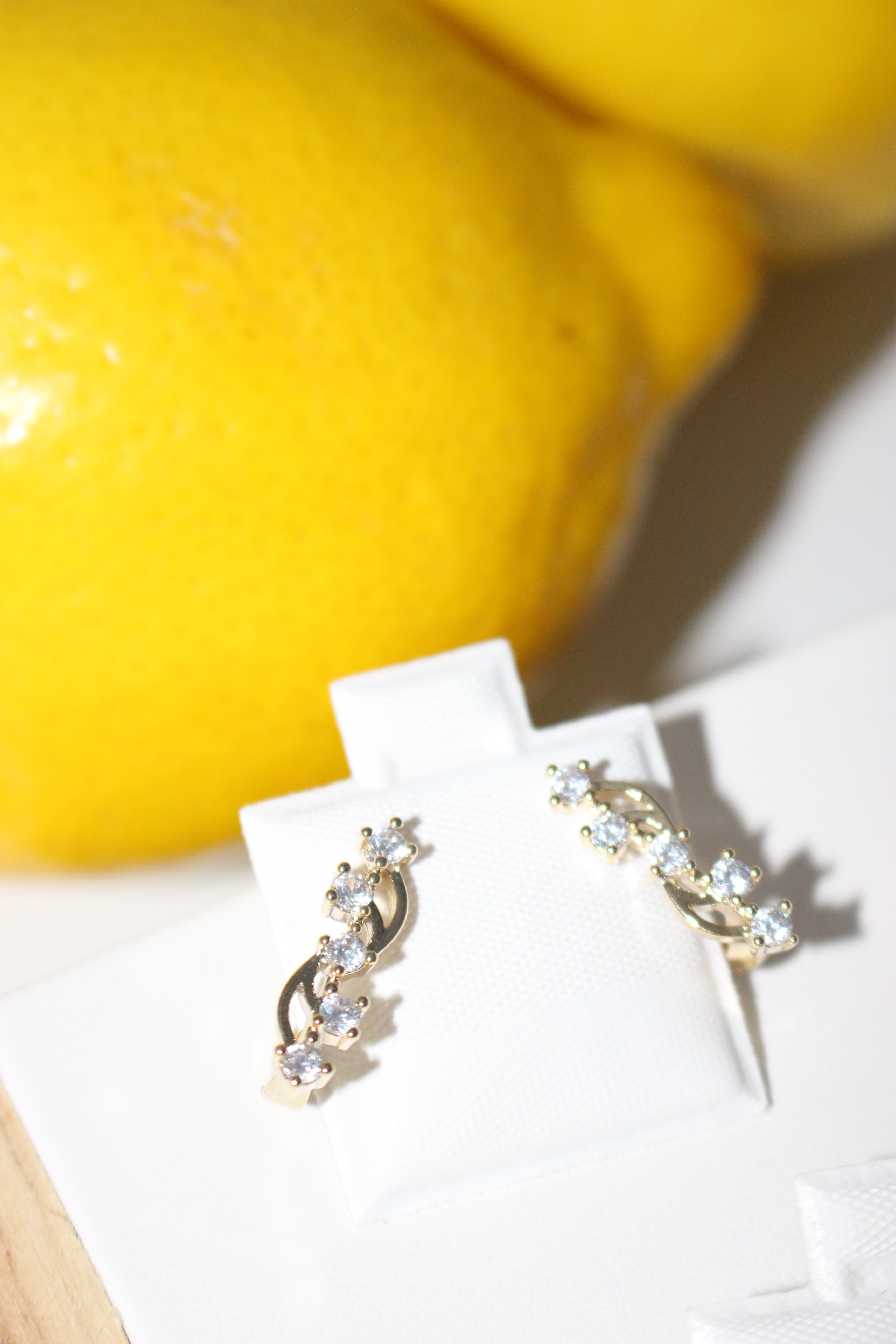Gold and crystal earrings on a white card with lemons in the background