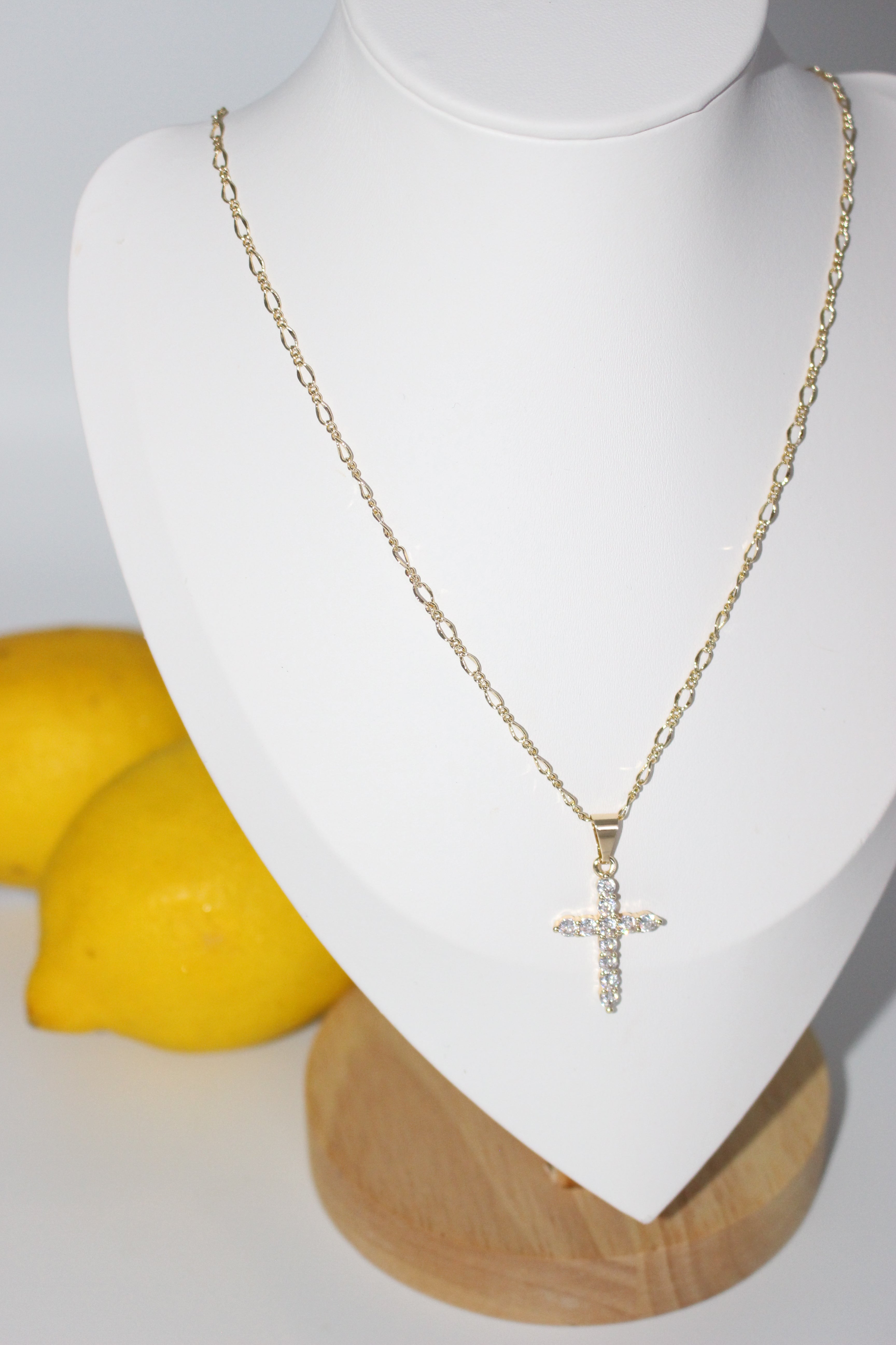Gold necklace on a mannequin bust with lemons in the background