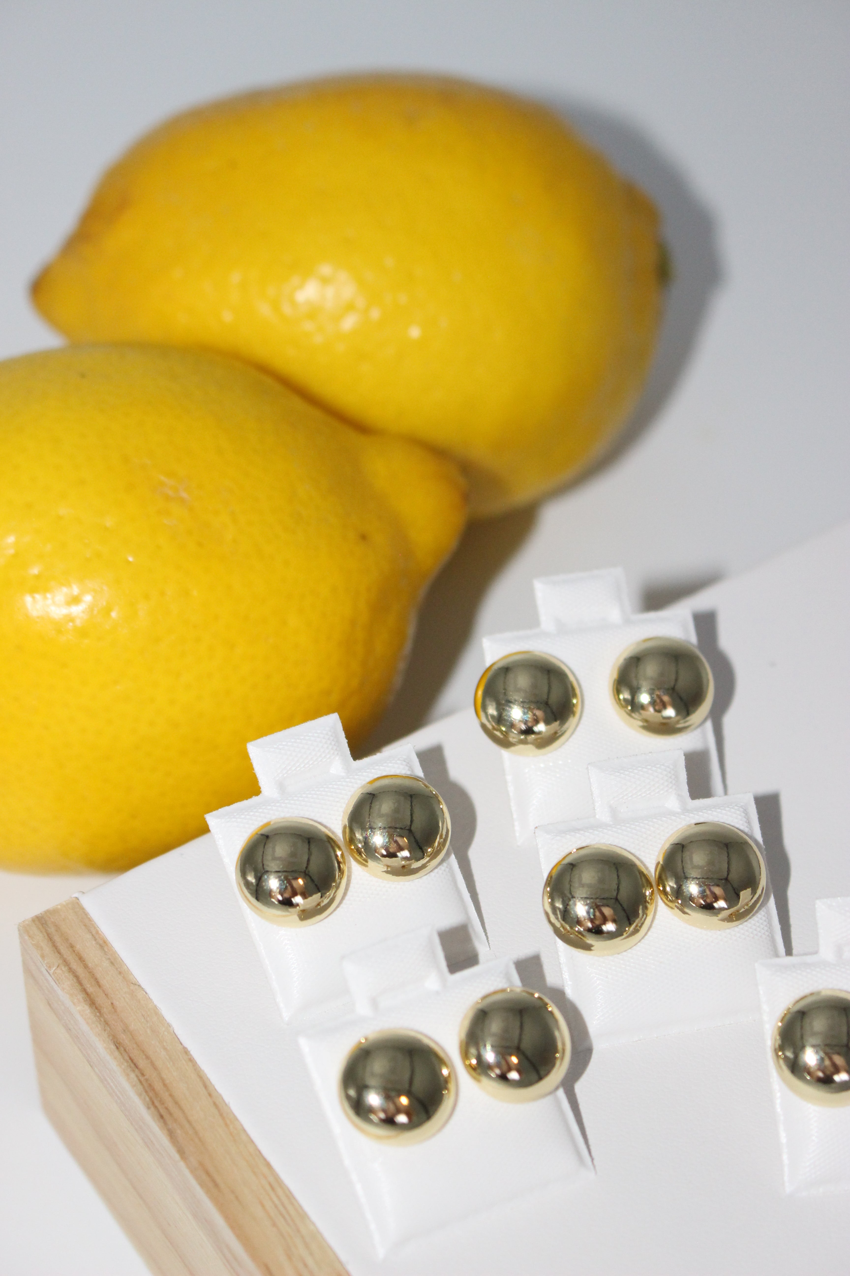 Earrings on white card with lemons in the background