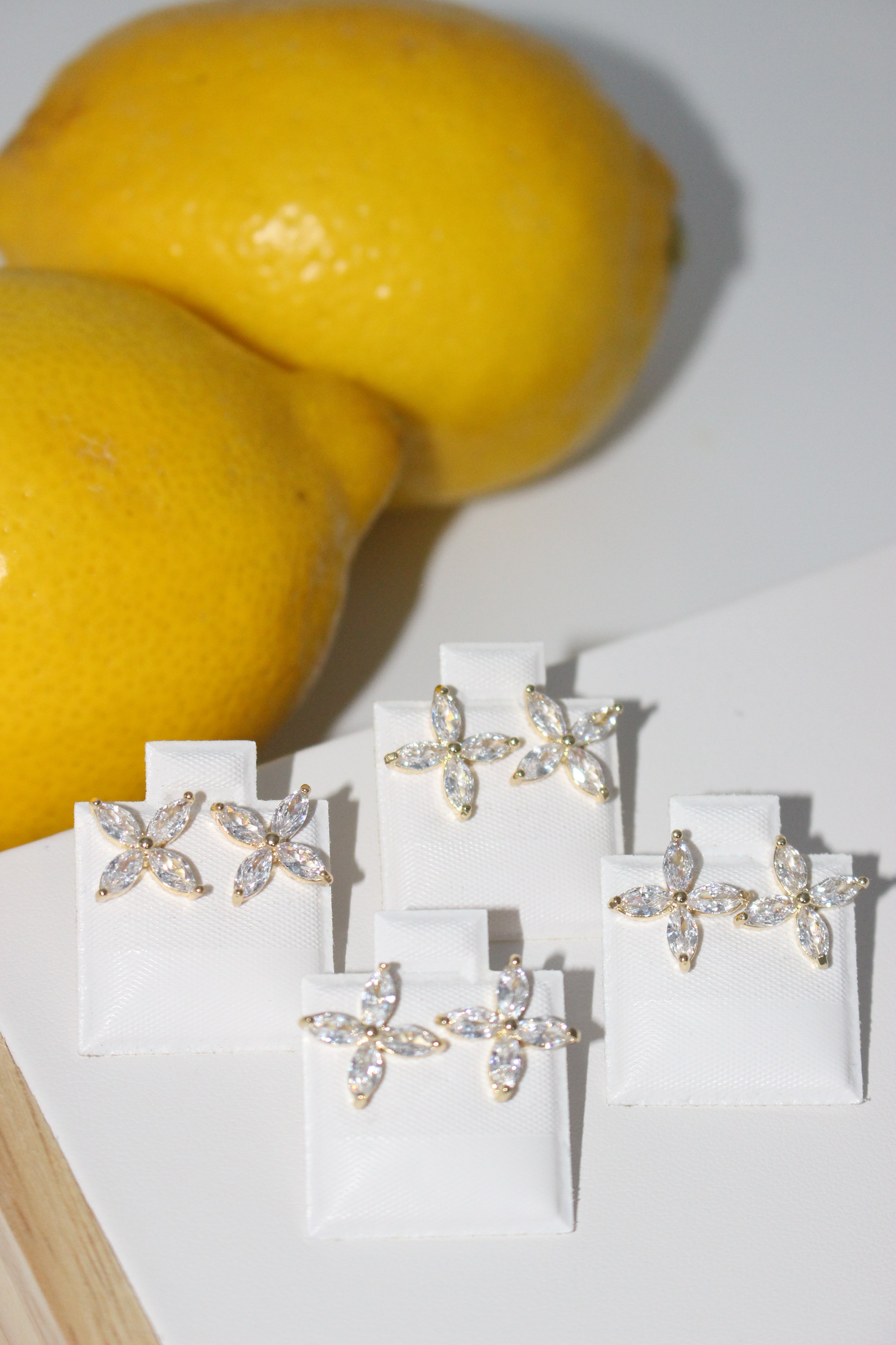 Pair of gold earrings on a white cloth with lemons in the background