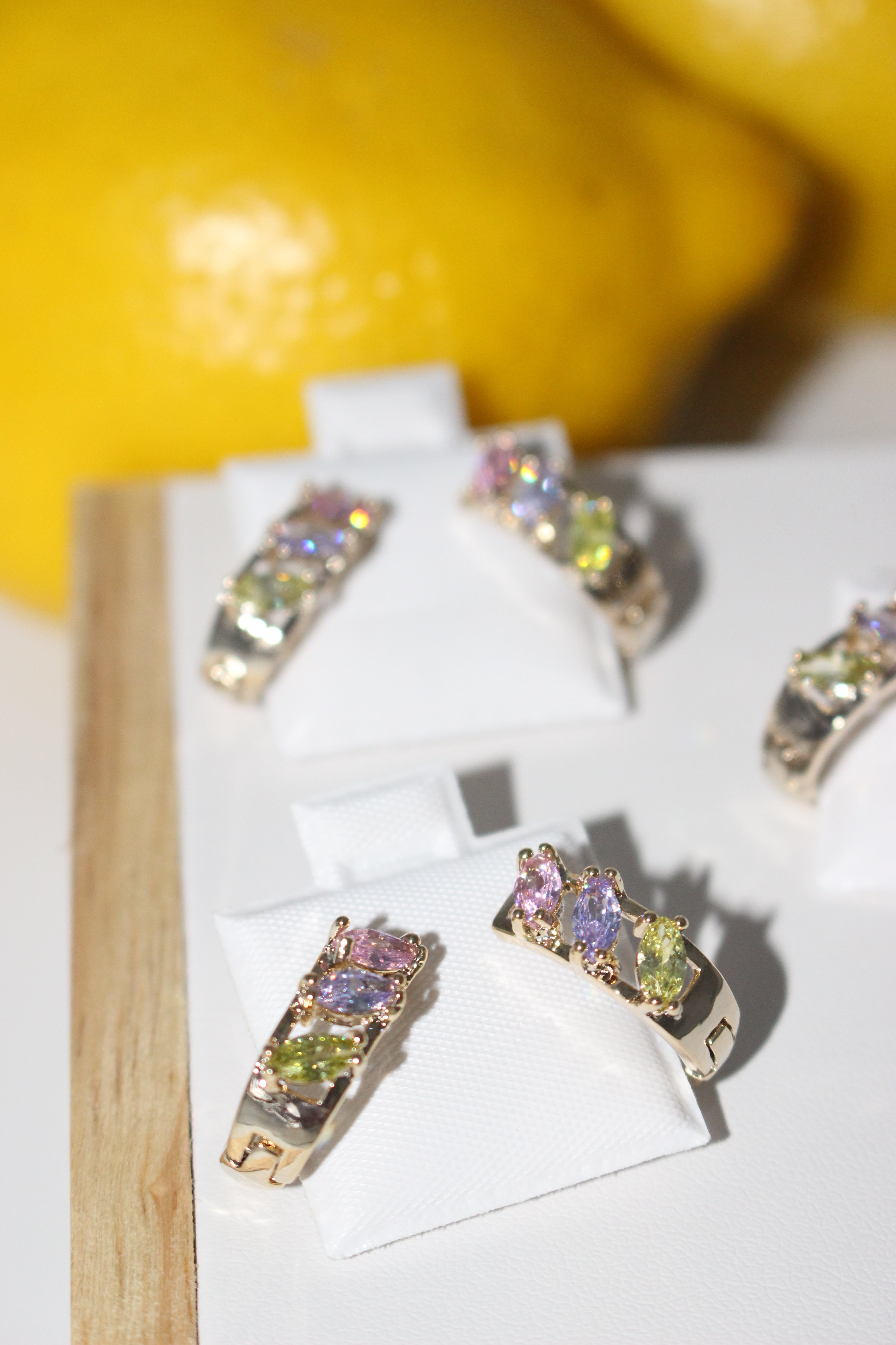 Colorful gemstone earrings on a white card with a yellow background