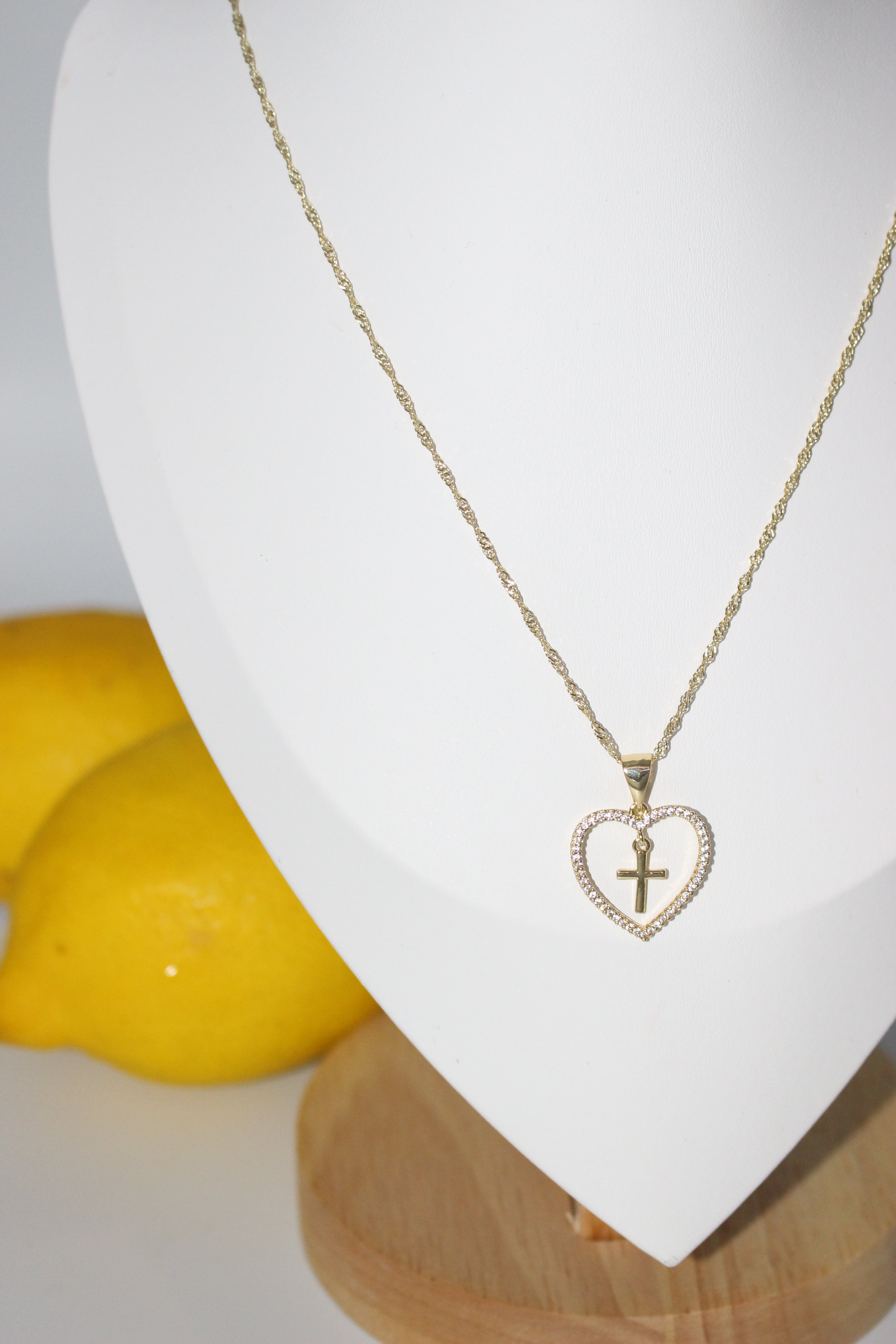 Necklace with a heart-shaped pendant featuring a Cross on a white surface.