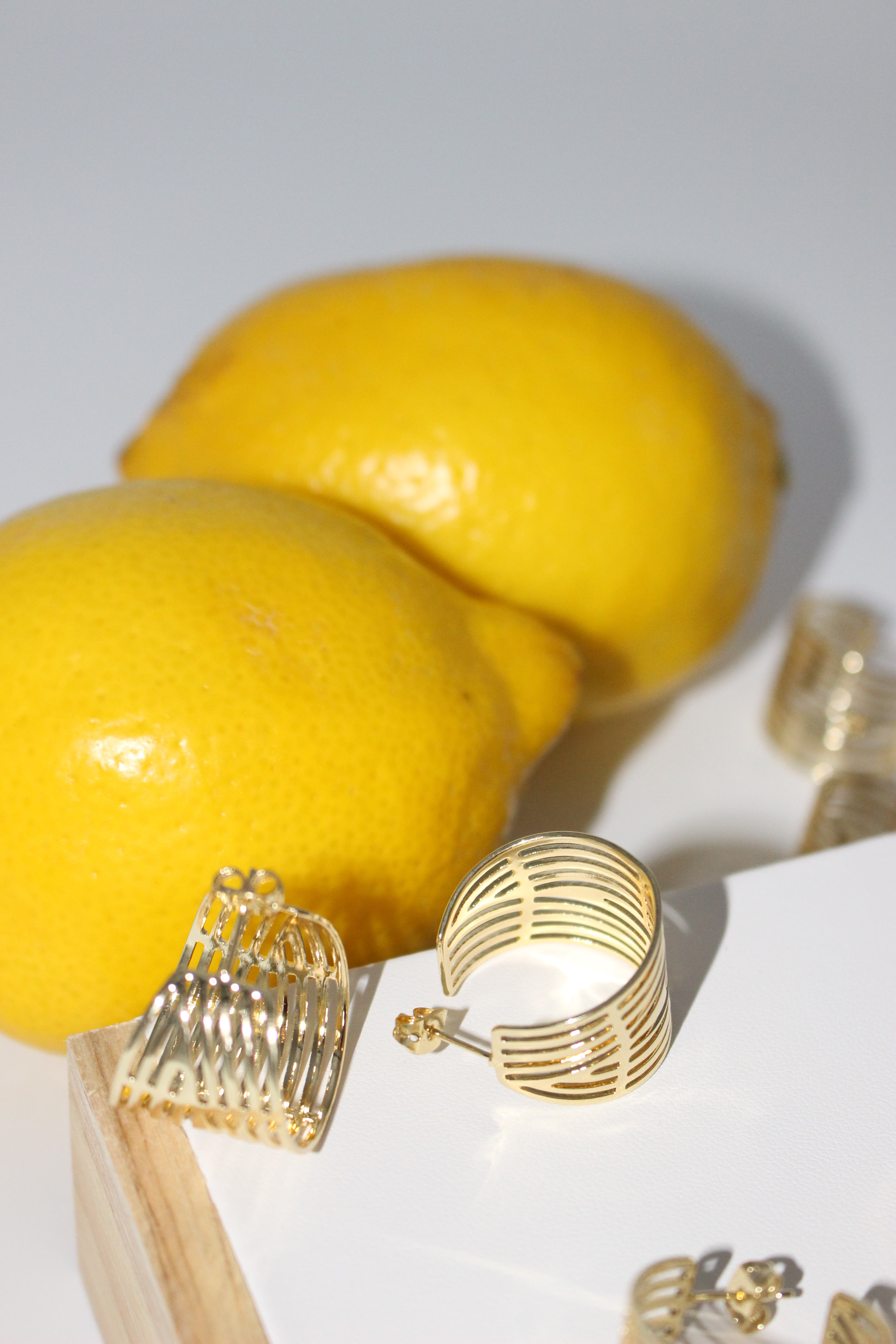 Gold hoop earrings with lemons on a white background