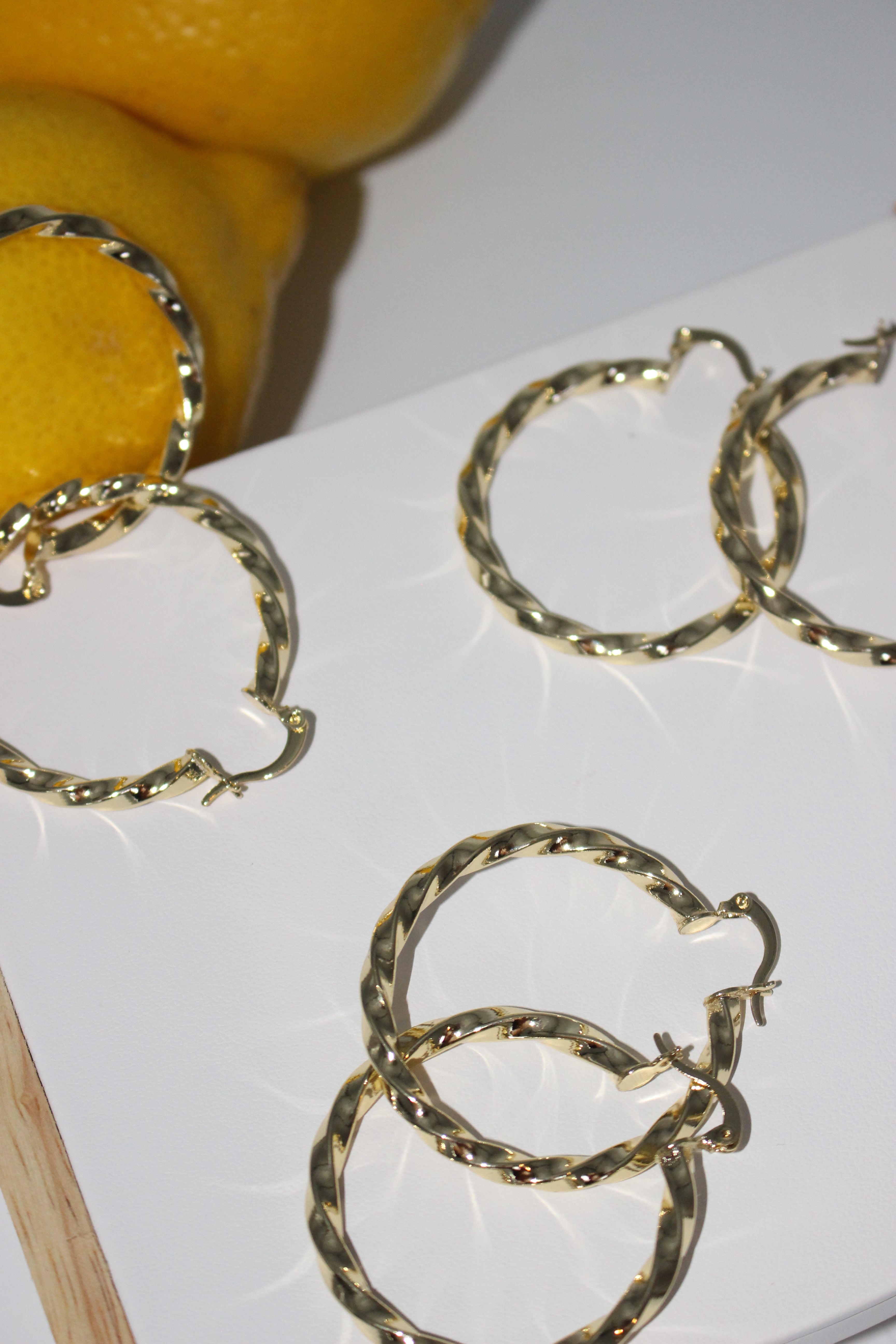 Hoop earrings on white surface with lemon fruit in background