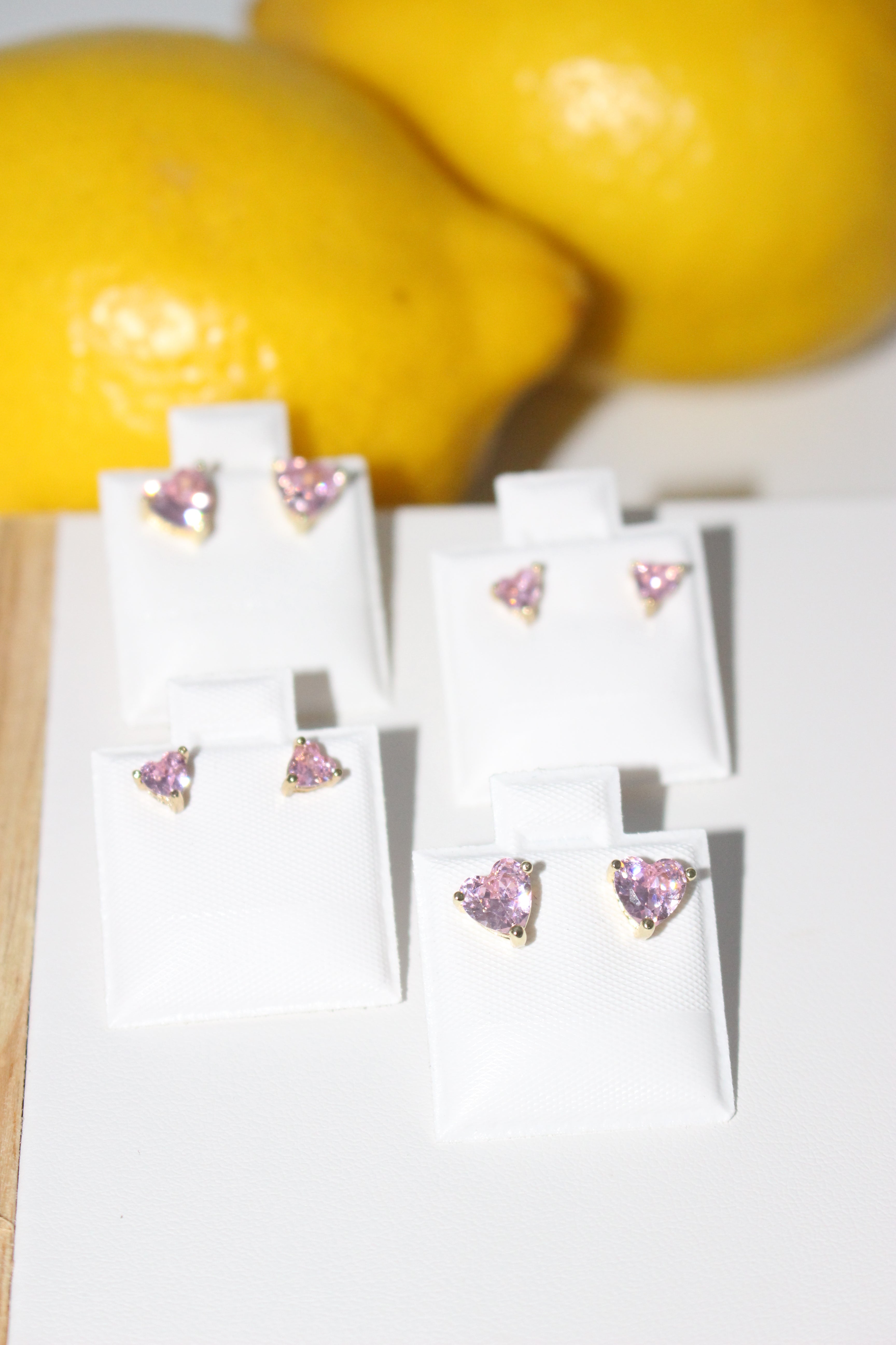 Pair of earrings with pink gemstones on a white card, surrounded by lemons.