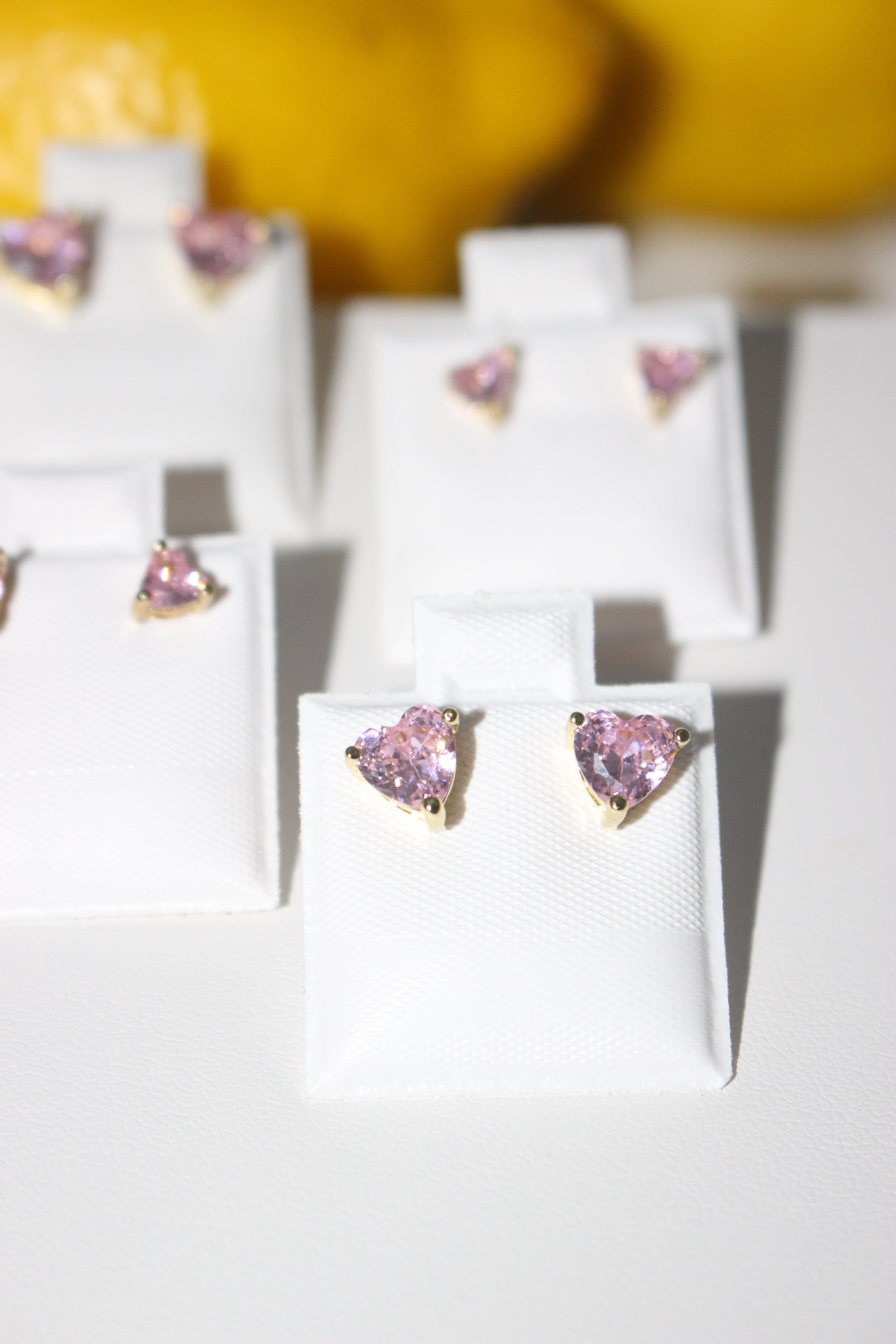 Pink heart-shaped earrings on white display cards with a blurred background