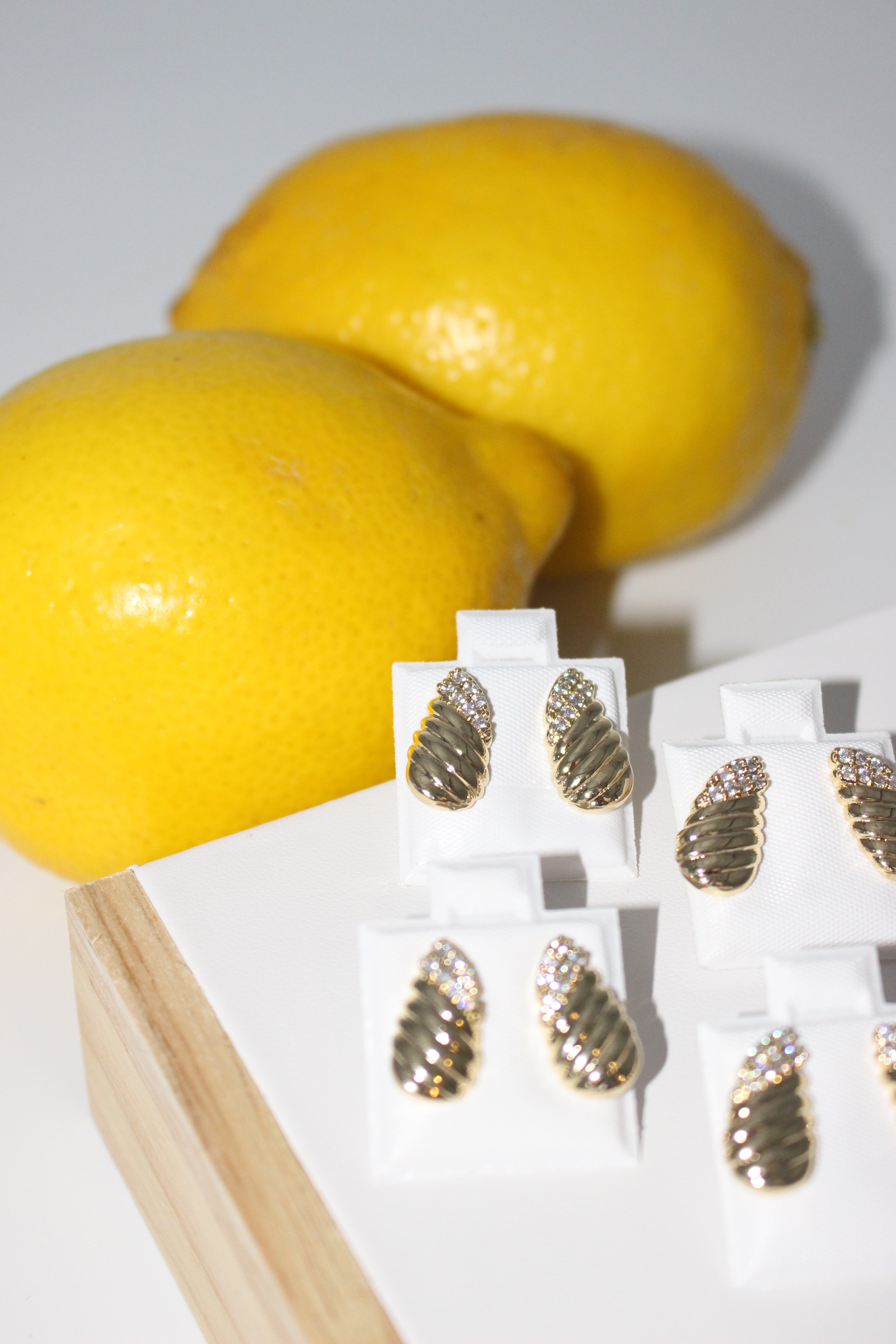 Gold leaf earrings on a white card with lemons in the background